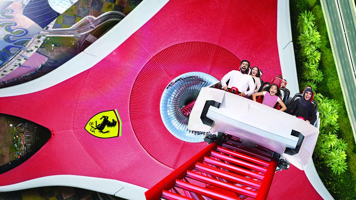 People on a roller coaster with a prominent Ferrari logo.