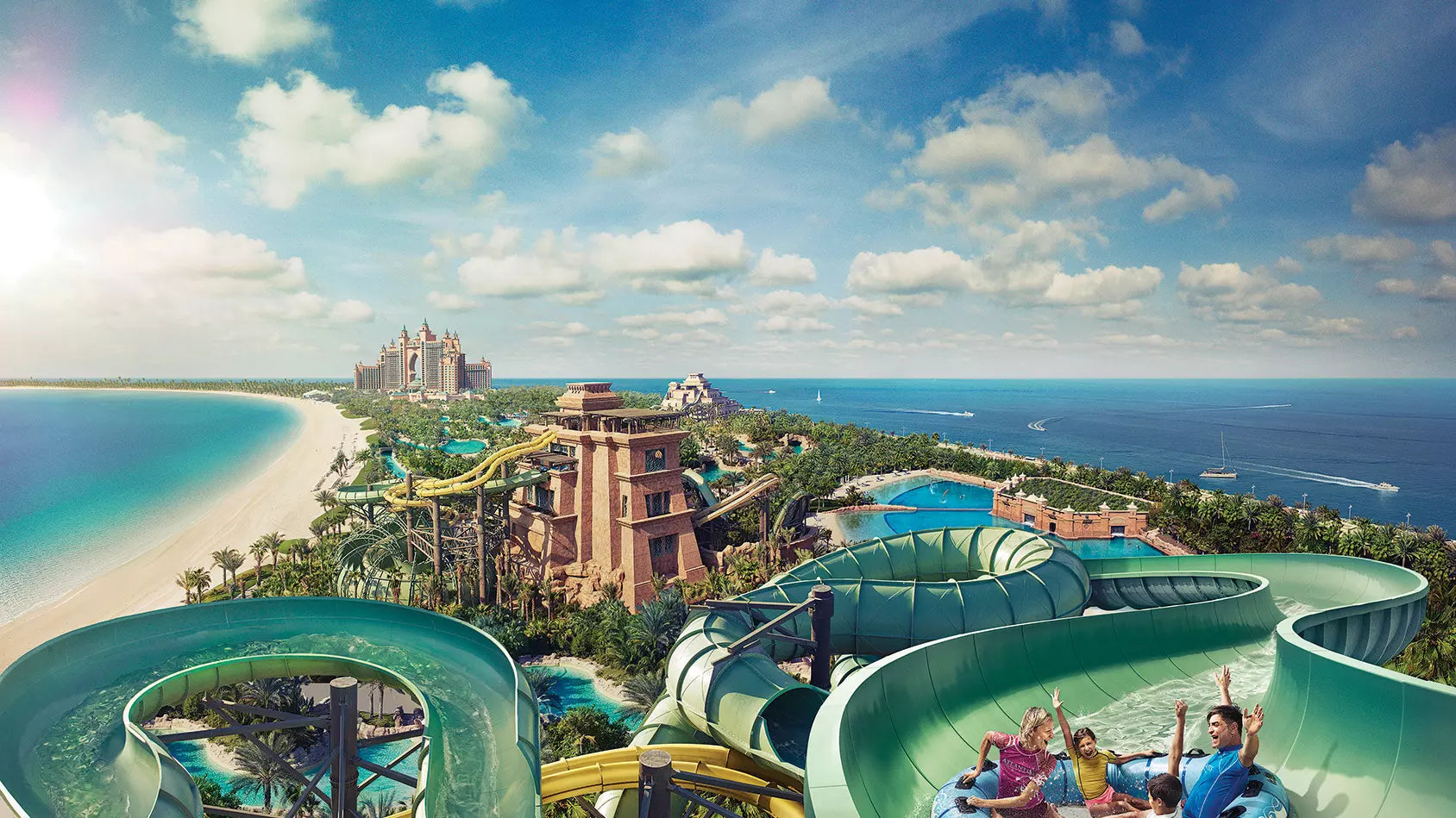 Water slides at a tropical resort with ocean and sky in the background