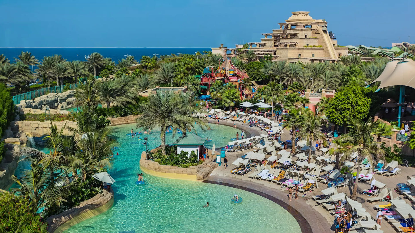 Luxury resort with pool and beach area, surrounded by palm trees and ocean view.