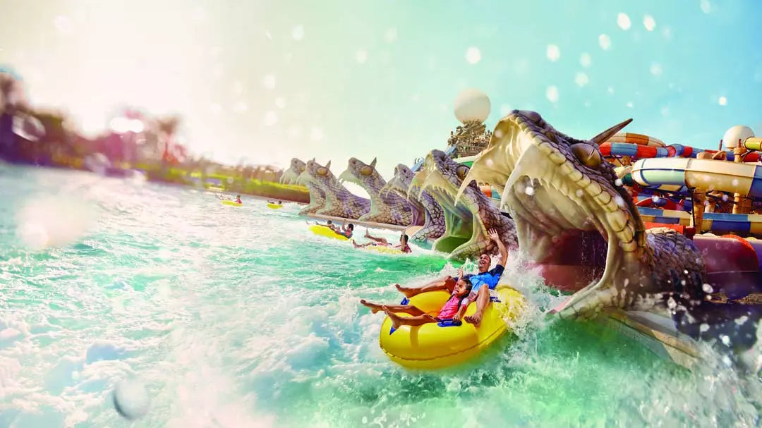People on a yellow raft being pulled by a large dragon-like water attraction at a water park.
